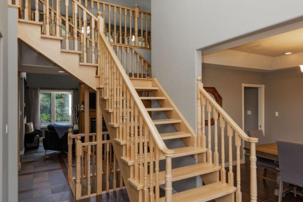Expansive wood staircase with multiple landings, banisters, and a view into the living and dining areas. - 14 Melissa Crescent, North Bay