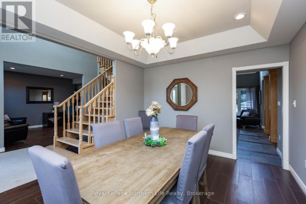 Formal dining room with a large wood table, upholstered chairs, chandelier, and a view of the foyer. - 14 Melissa Crescent, North Bay