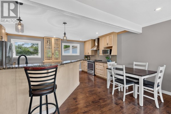 Kitchen and dining area with light wood cabinets, granite island, wooden dining table, and chairs. - 14 O'regan Road, St  John S