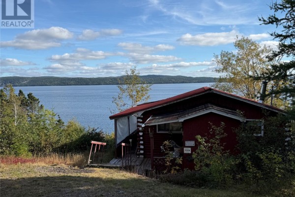 Exterior view of the cabin with a red facade and a large body of water behind it. - 14 Old Country Road, Point Of Bay
