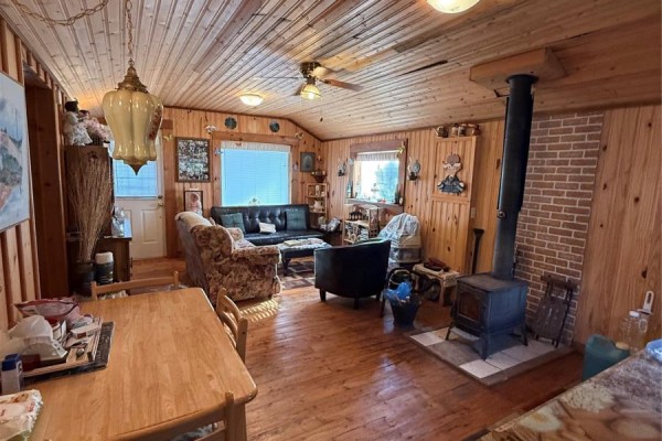 Interior view of the living space showing a wood stove, sofa, chairs, and dining table. - 14 Old Country Road, Point Of Bay
