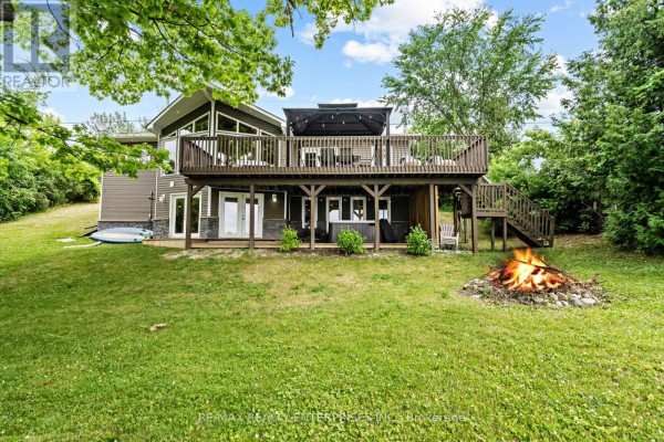 Backyard view of a multi-level house with a large wooden deck and a hot tub. - 14 Parker Drive, Alnwick/haldimand