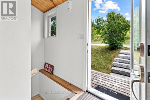 Interior view of a small white entryway with a wooden shelf and an open door showing stone steps outside. - 14 Parker Drive, Alnwick/haldimand