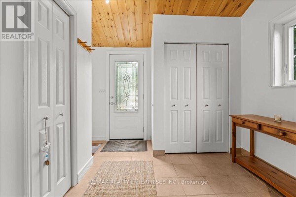 Interior view of a white entryway with a glass-paned door, wood ceiling, and double closet doors. - 14 Parker Drive, Alnwick/haldimand
