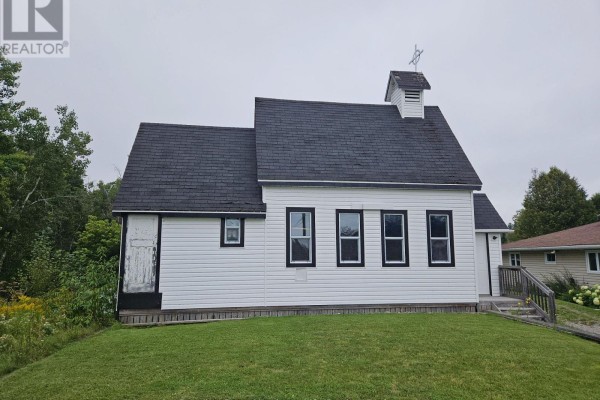 Rear view of the white building with a black roof and grassy slope. - 14 Parkwood Lane, Temagami