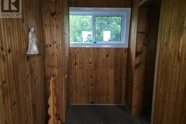 Interior room with wood paneling and a window showing an outdoor view. - 14 Parkwood Lane, Temagami