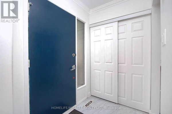 Interior entryway with a large dark blue front door, a narrow window, and white sliding closet doors. - 14 Pilkington Crescent N, Whitby