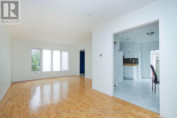 Living room with light wood floors, white walls, and a large bay window overlooking greenery. - 14 Pilkington Crescent N, Whitby
