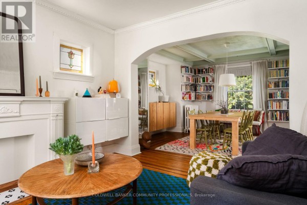 View of living room and dining area with archway, bookshelves, and wooden dining table. - 14 Prospect Street S, Hamilton