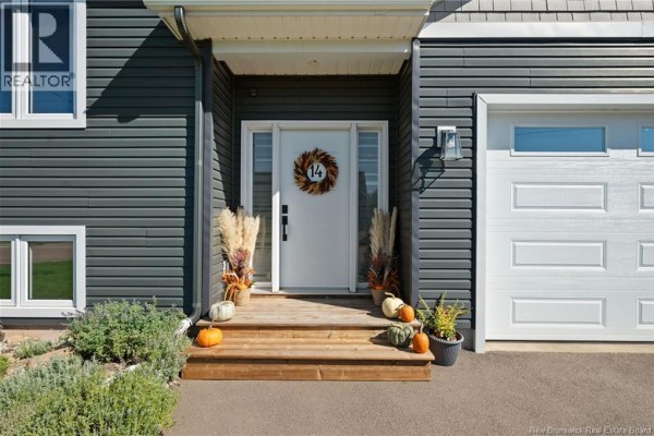 Front entrance with a white door, wooden steps, and fall decorations. - 14 Robert Street, Shediac