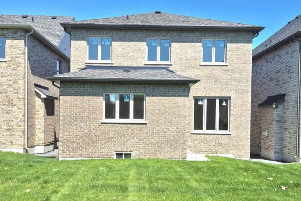 Rear exterior of the house showcasing beige brick and multiple white-framed windows. - 14 Rogerson Street, Clarington