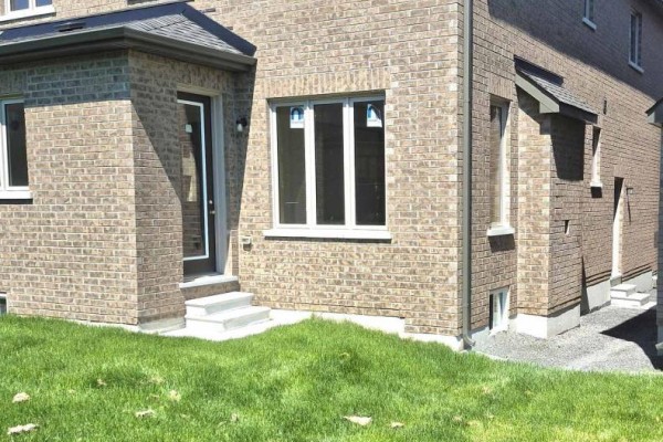 Side exterior of the house with a glass door and beige brick construction. - 14 Rogerson Street, Clarington
