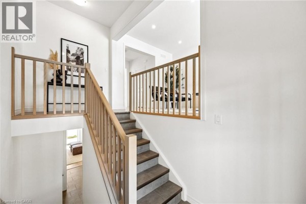 Landing area with wooden railing and decorative vase on table. - 14 Sora Lane, Guelph