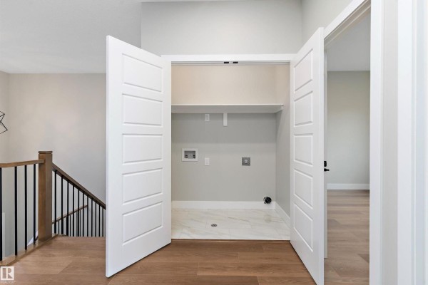 Hallway laundry closet with white bi-fold doors, tile floor, and hookups for washer and dryer. - 14 Southbridge Dr, Calmar