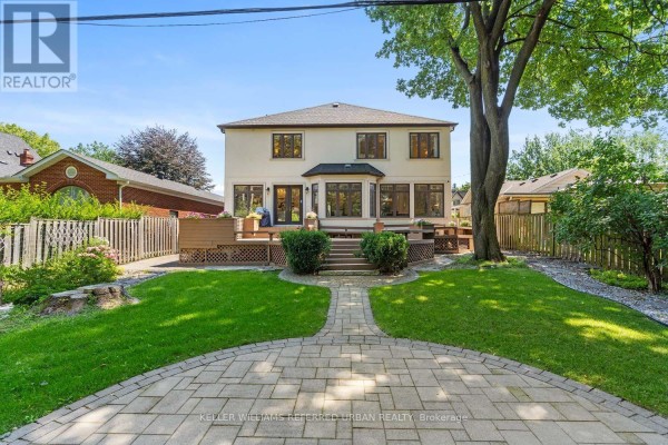 Open-concept kitchen and dining area with a large wooden table and bay windows. - 14 Tremont Crescent, Toronto