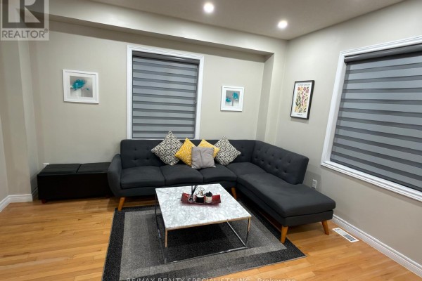 Living room with a sectional sofa, marble coffee table, and striped blinds. - 14 Viceroy Crescent, Brampton