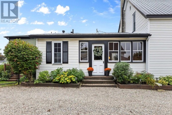 Side entrance of a white house with steps, planters, and a white door. - 14 Victoria Avenue, North Grenville