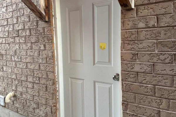 White paneled door on a tan brick wall with exposed wooden beams above. - 14 Whitbread Crescent, Ajax