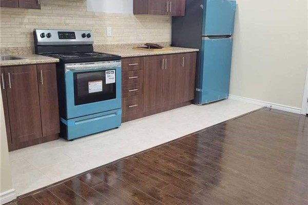 Kitchenette with dark brown cabinets, light granite counters, and a teal stove. - 14 Whitbread Crescent, Ajax