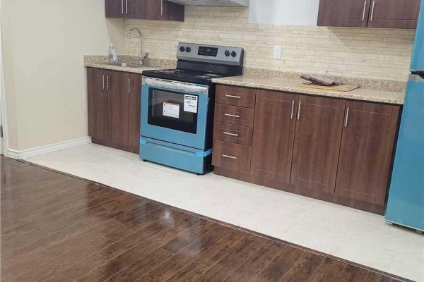 Corner view of a kitchenette with dark brown cabinets, teal refrigerator, and teal stove. - 14 Whitbread Crescent, Ajax