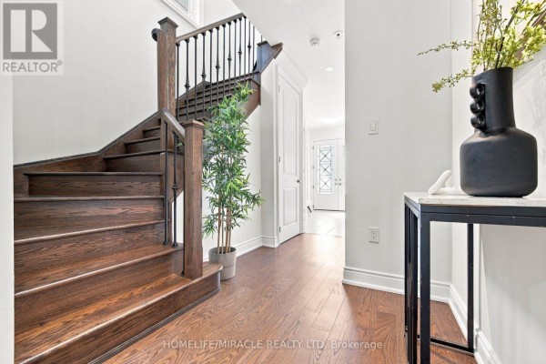 Hallway with dark wood staircase, wrought iron banisters, hardwood floors, and console table - 14 Zenith Avenue Vaughan