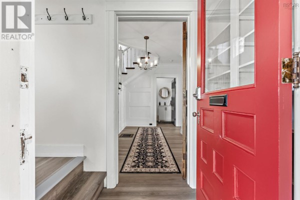 View from inside an open red door looking into a hallway with stairs. - 140 Pleasant Street Street, Truro