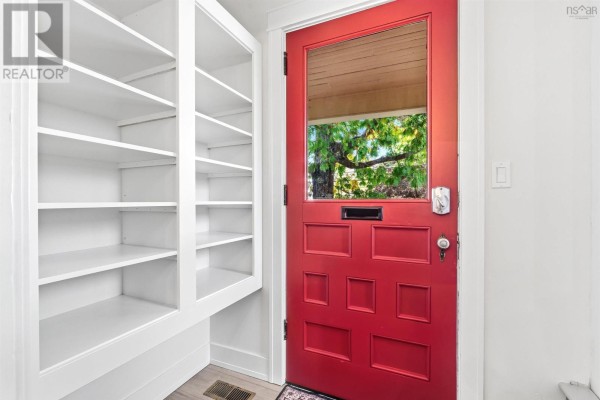 Interior view of a room with white built-in shelves and a red screen door. - 140 Pleasant Street Street, Truro