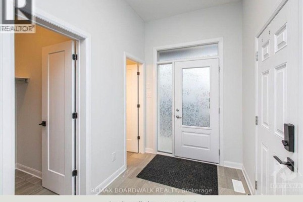 Entrance foyer with a frosted glass front door, tiled floor, and white paneled interior doors. - 140 Shallow Pond Place N, Ottawa
