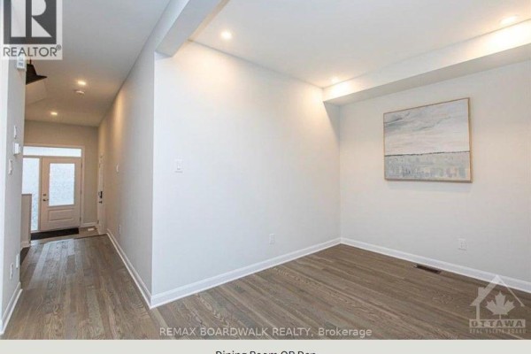 Empty dining room with light grey walls, wood-look laminate flooring, and a modern painting on the wall. - 140 Shallow Pond Place N, Ottawa