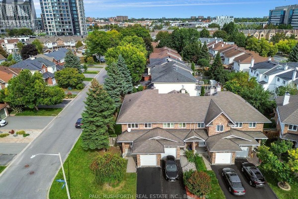 Aerial view of a townhouse complex with garages, driveways, and surrounding greenery. - 140 Thornbury Crescent, Ottawa