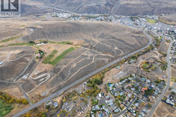Aerial view showing residential areas, dry hills, and a highway connecting to Cache Creek. - 1400 Fehr Way, Cache Creek