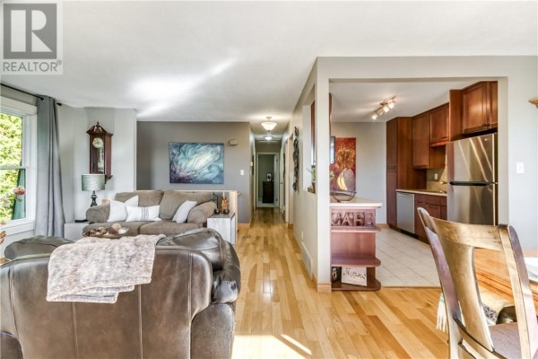 Living room with brown leather chairs, a beige sofa, glass coffee table, and wood floor. - 1400 Magnolia Boulevard, Sudbury