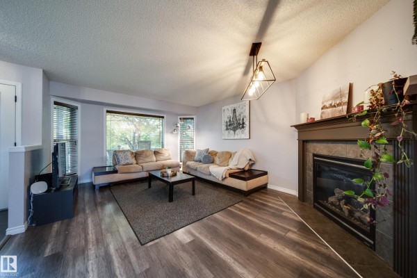 Living room with beige sectional sofa, dark coffee table, and gas fireplace. - 14006 158a Av Nw, Edmonton