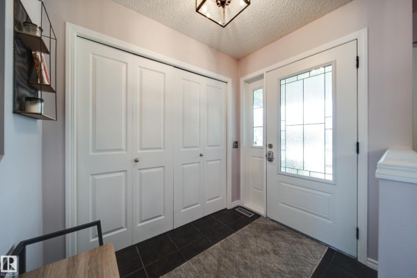 Entryway with white double doors, a glass-paned front door, and dark tile flooring. - 14006 158a Av Nw, Edmonton