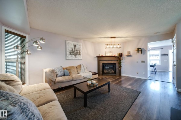 View of the living room with a sectional sofa, fireplace, and entryway to kitchen. - 14006 158a Av Nw, Edmonton