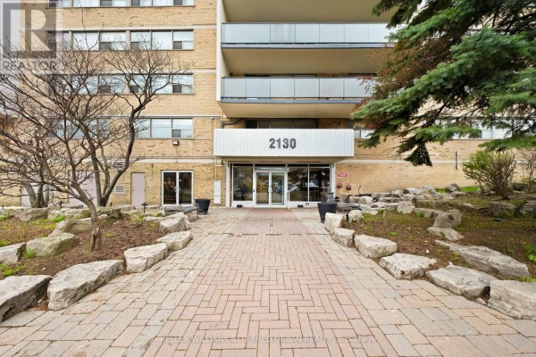 Entrance walkway to the apartment building with brick paving and large rocks. - 1401 - 2130 Weston Road, Toronto