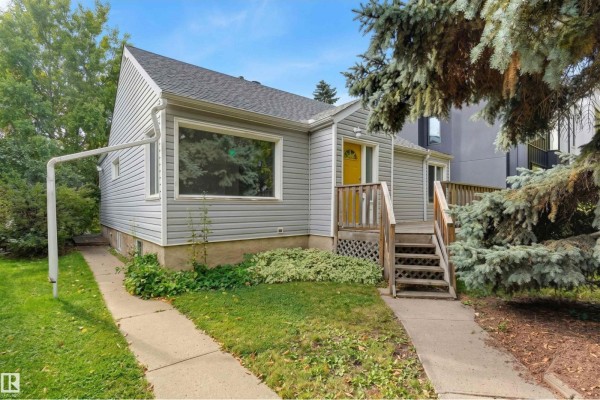 Front exterior of a light blue house with grey siding and a yellow front door. - 14019 106 Av Nw, Edmonton