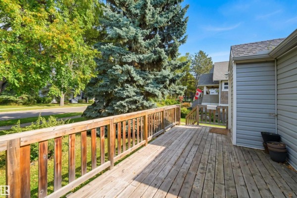 Wooden deck with railings overlooking a tree-lined street and neighboring houses. - 14019 106 Av Nw, Edmonton