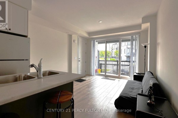 View of kitchen counter and living space with sliding glass doors. - 1402 - 160 Densmore Road, Cobourg