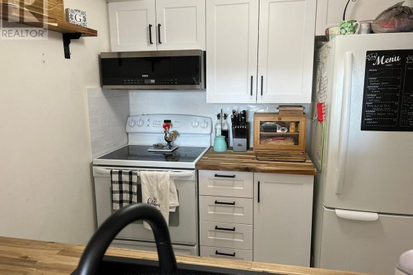 Compact kitchen with white cabinets, white appliances, and a stainless steel microwave. - #1402 - 3 Hickory Tree Road, Toronto