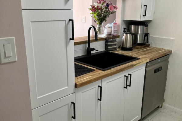 Kitchen with white cabinets, black sink, wooden countertop, and a dishwasher. - #1402 - 3 Hickory Tree Road, Toronto