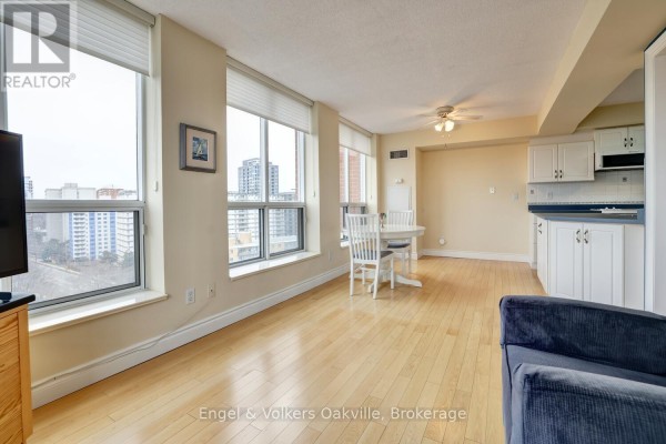 Living room with hardwood floors, dining table, and kitchen - 1402 - 442 Maple Avenue Burlington