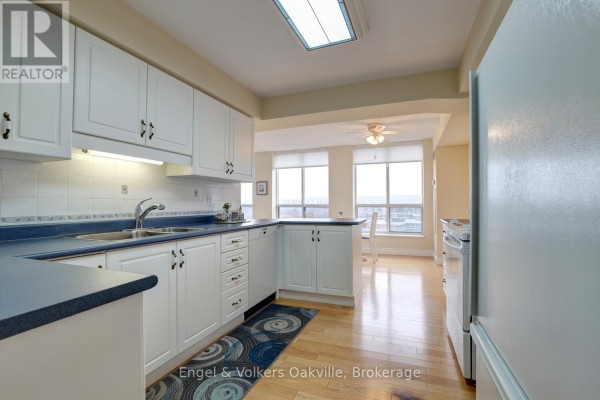 Kitchen with white cabinets, blue countertops, double sink, and hardwood floors - 1402 - 442 Maple Avenue Burlington