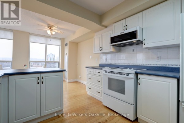 Kitchen with white cabinets, tile backsplash, white stove, and blue countertops - 1402 - 442 Maple Avenue Burlington