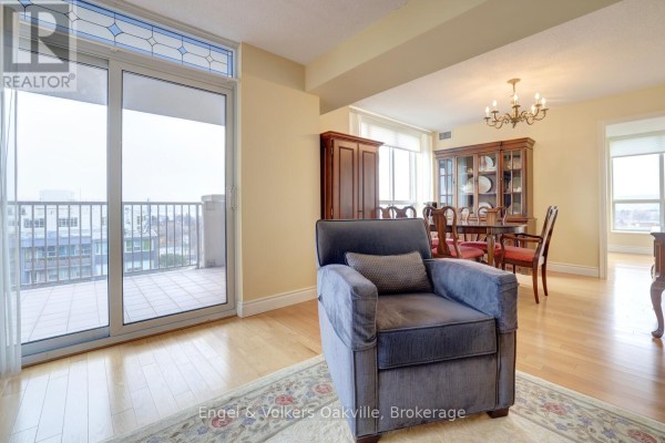 Living room with armchair, dining table, hutch and balcony - 1402 - 442 Maple Avenue Burlington