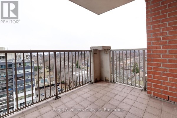 Balcony with tiled floor and brick accent wall overlooking neighborhood - 1402 - 442 Maple Avenue Burlington