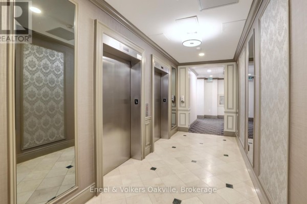 Hallway with double elevators, mirrors, patterned wallpaper, and marble tile floor - 1402 - 442 Maple Avenue Burlington