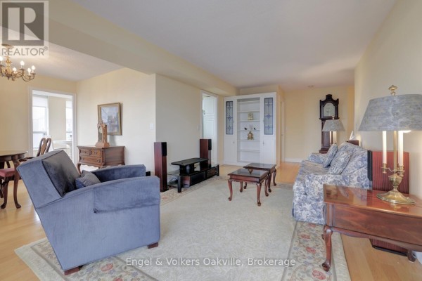 Floral sofa, blue armchair, coffee tables, and bookshelf in living room - 1402 - 442 Maple Avenue Burlington