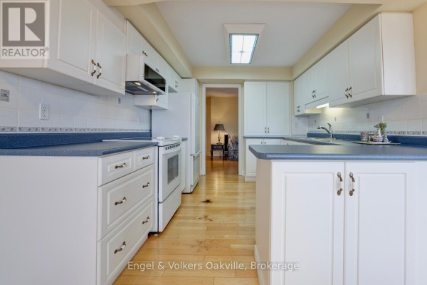 Kitchen with white cabinets, blue countertops, and white appliances - 1402 - 442 Maple Avenue Burlington