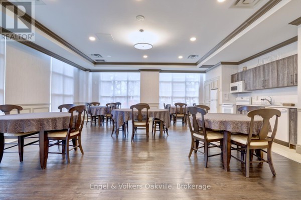 Dining room with tables, chairs, and kitchenette - 1402 - 442 Maple Avenue Burlington